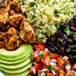 Easy burrito bowl with chicken, cilantro-lime rice, black beans, pico de gallo, and sliced avocado in a white bowl