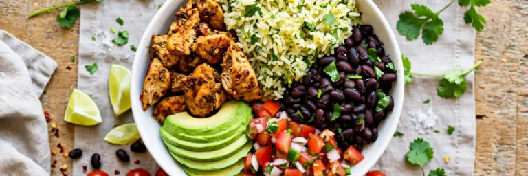 Easy burrito bowl with chicken, cilantro-lime rice, black beans, pico de gallo, and sliced avocado in a white bowl